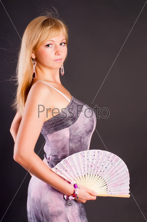 Young woman with fan over black background