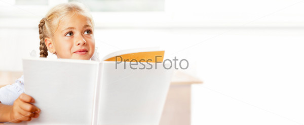 Image of smart child reading interesting book in classroom.