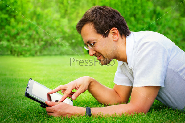 Adult man working with tablet computer outdoor in park