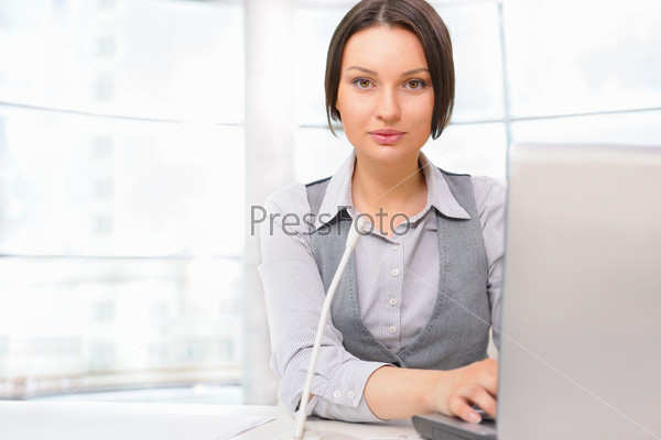 Business woman working with laptop at her office. Talking online by microphone with partners, colleagues or clients