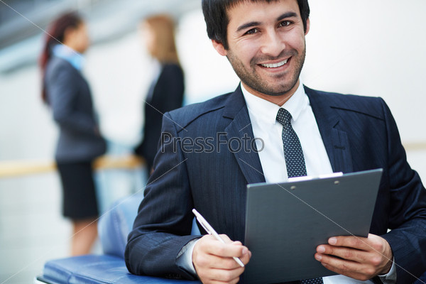 Portrait of friendly male leader looking at camera in working environment
