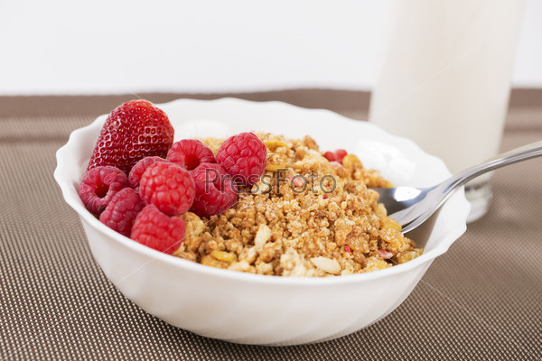Berries on golden cereals in bowl with spoon