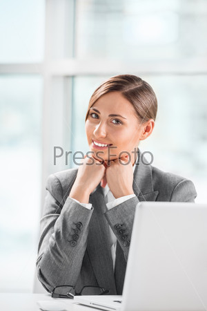 Portrait of smiling caucasian female executive working on laptop and making pause