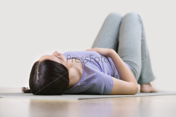 Portrait of a young fitness woman lying on a yoga mat and exerci