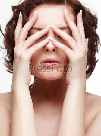 portrait of beautiful brunette young woman with french manicure closing eyes with manicured hands
