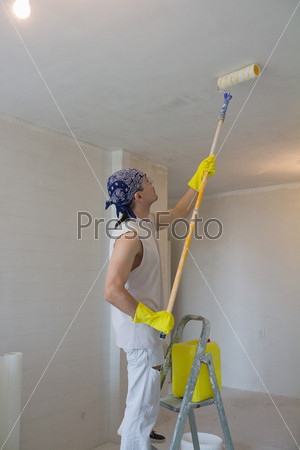Young man painting ceiling with painting roller