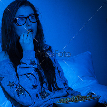 Young woman watching scary movie at home darkness