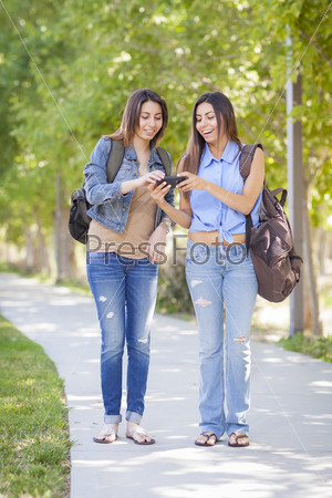 Young Adult Mixed Race Twin Sisters Sharing Cell Phone Experience Outside.