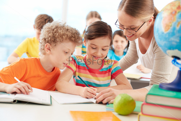 Portrait of diligent schoolgirl drawing at lesson surrounded by her classmate and teacher