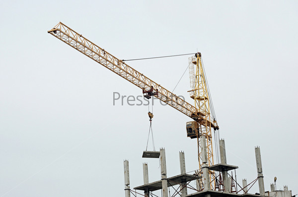 yellow construction tower crane arm against blue sky