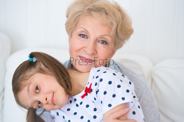 Lovely little girl with her grandmother having fun and happy moments together at home