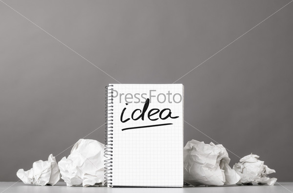 creative process. crumpled wads and notebook with word idea