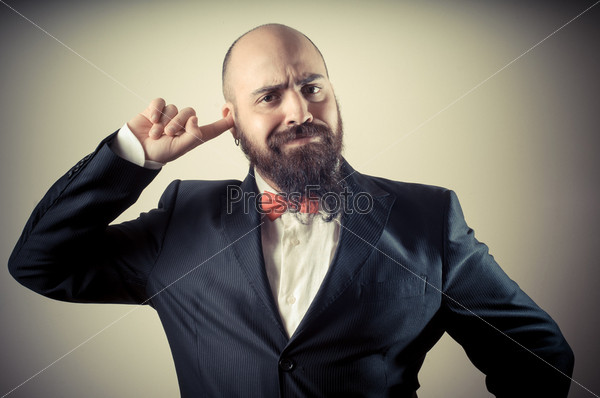 funny elegant bearded man with finger in the ear on vignetting background