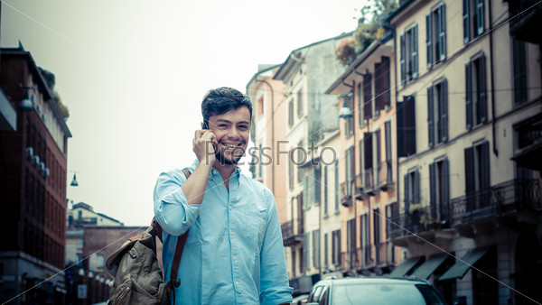 stylish man in the street at the phone in the city