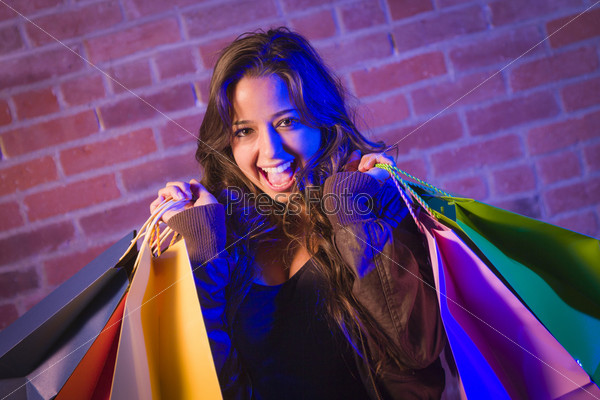 Молодая женщина, держащая сумки, у кирпичной стены
