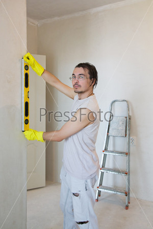 Young worker with spirit level working on home renovations