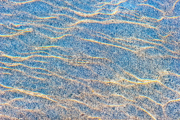 Sun reflections on a marble slab in pool water from above.