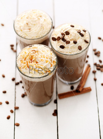 Ice coffee with whipped cream and coffee beans on a white table