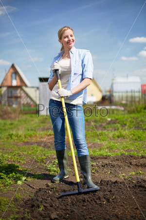 Image of happy female farmer looking at camera while working in the garden