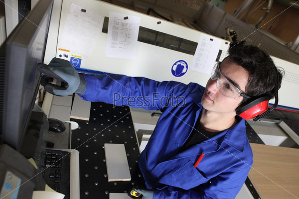 Young blue collar in factory with computer