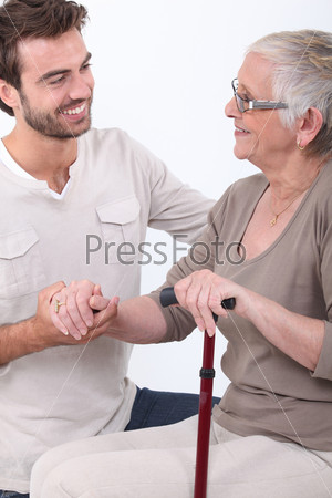 Молодой человек помогает пожилой женщине