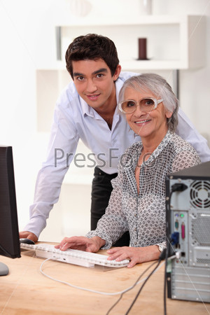 grandson explaining to his grandmother how to use a computer