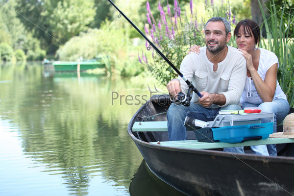 Пара рыбачит в маленькой лодке на реке
