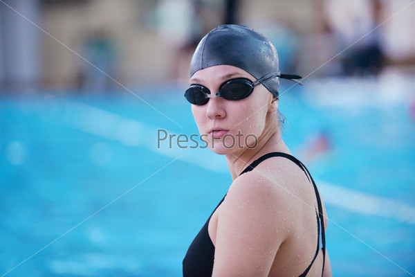 Happy muscular swimming woman  wearing glasses and cap at swim pool and represent health and fit concept