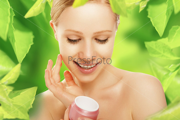 beauty young woman with cream and a natural skin care in herbal green background
