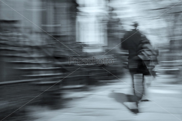 man walking on a city street in motion blur, brownstone buildings as a background, rear view