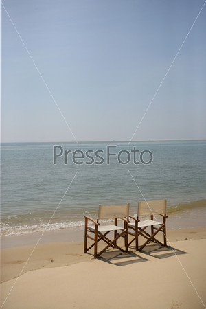 Folding chairs on the sand at the edge of the sea