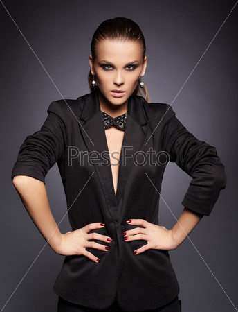 portrait of beautiful young brunette woman in black jacket and fancy collar on dark gray