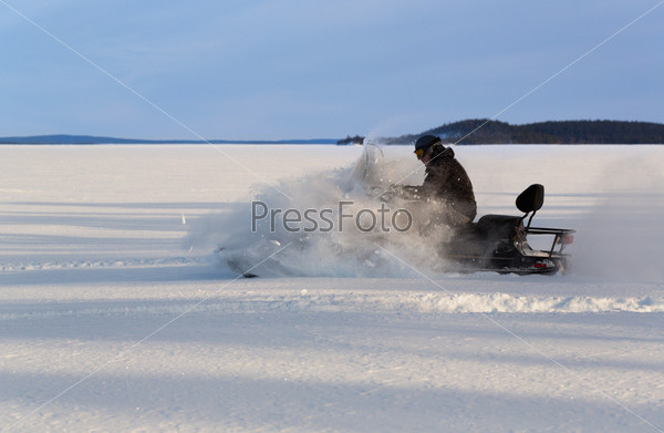 Man rushes a snowmobile on a snow plain, stock photo