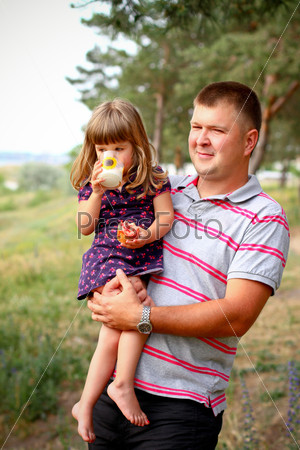 Little girl with dad in the forest, girl drinking milk and eating bread, stock photo