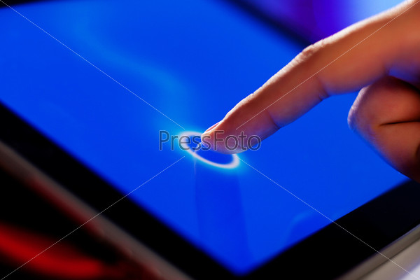 Closeup of finger touching blue toned screen on tablet-pc