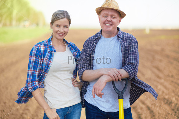 Image of two happy farmers on background of plowed field