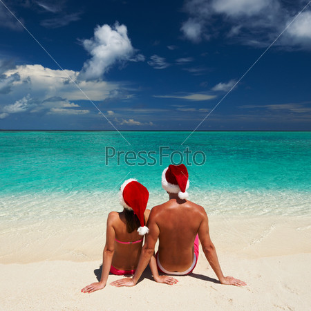 Couple in santa\'s hat on a tropical beach at Maldives
