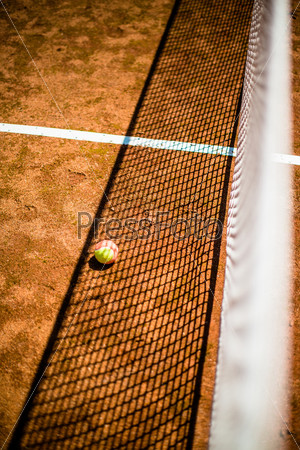 abstract: tennis ball and net with great shadows on court