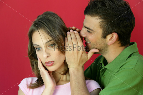 Man whispering a secret to a young woman, stock photo