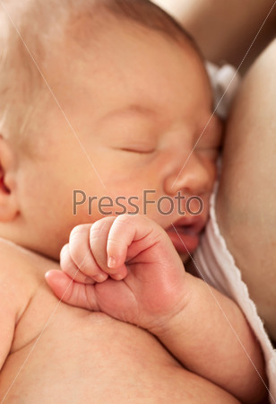 Newborn baby sleeping in mother\'s arm after breastfeeding