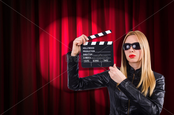 Girl with movie board against curtains, stock photo