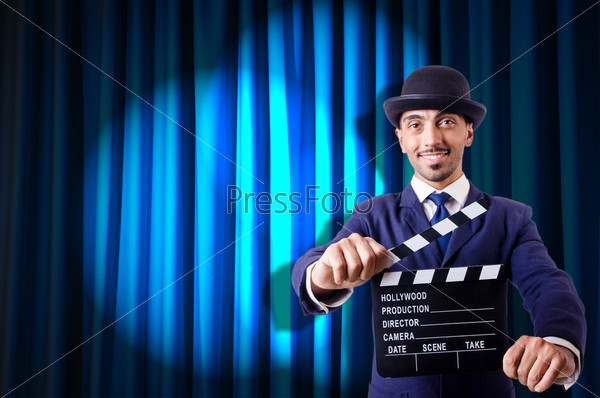 Man with movie clapper on curtain background