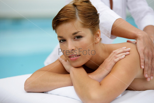 Woman receiving back massage by the pool