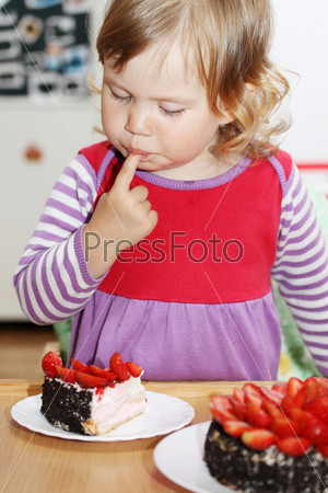 The little blue-eyed girl eating cake with strawberries, stock photo