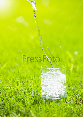 Water poured into glass. Pure water on green bacground