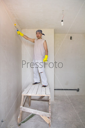 Worker painting wall with painting roller