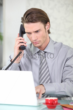 Businessman phoning in front of a laptop computer