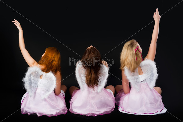 Three beautiful women wearing angel\'s wings. Back view