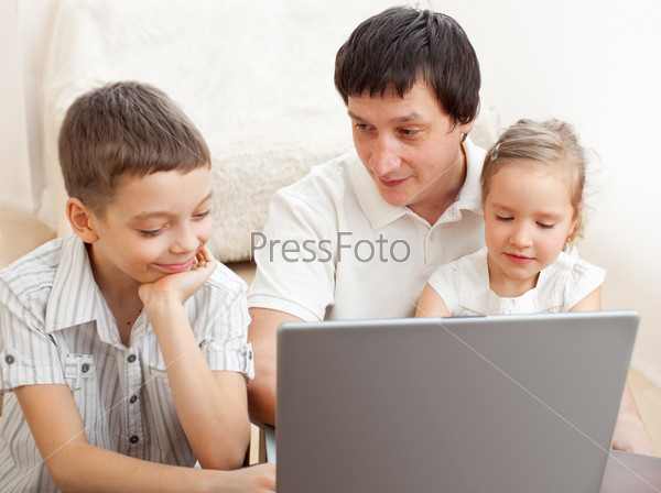 Happy family with laptop. Father with children play in the computer
