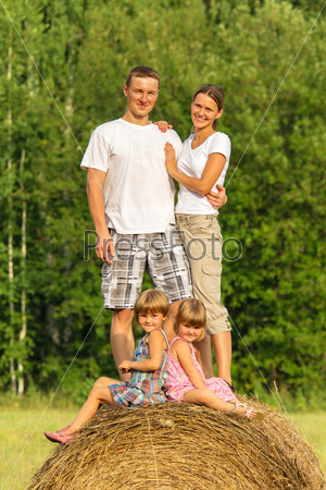 Happy family with two children on haystack in summer day